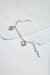 Pulsera de cadena rolo de plata con dos dijes colgantes en forma de corazón.