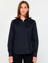 Camisa de manga larga color negro con cuello clásico y cierre frontal de botones. Presenta detalles de flores bordadas en relieve sobre los hombros y el pecho.