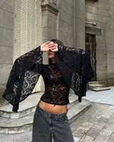 Blusa de encaje negro con diseño floral, de corte ajustado al cuerpo y mangas largas con terminación acampanada y amplia.