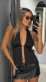 Top negro con escote halter profundo, diseño con aberturas frontales y detalle de pequeños puntos brillantes en toda la prenda.