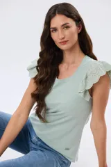 Remera de algodón color beige, de manga corta con volados de broderie, escote redondo y cuerpo liso.
