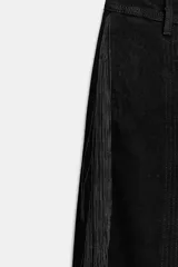 Pantalón negro de tiro medio confeccionado en algodón, con cintura con trabillas, corte amplio y detalle de flecos a tono en los laterales. Cierre frontal con cremallera, botón y ganchos metálicos.