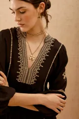 Vestido corto de viscosa crepe color negro, con escote en V, mangas largas abullonadas y detalles de bordado en hilo a contratono en el escote, mangas y ruedo.