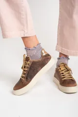 Zapatillas bajas de cuero color marrón con estrella beige en el lateral, cordones color beige y detalle dorado en el talón.