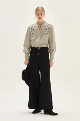 Jean de tiro alto, pierna ancha y color negro. Presenta costuras marcadas en el frente que recorren verticalmente la pierna.