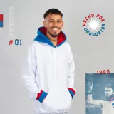 Canguro blanco con capucha forrada en azul y puños en rojo y azul. Diseño holgado con bolsillo delantero tipo canguro.