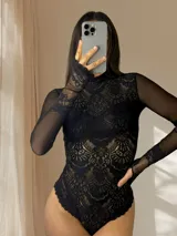 Body de encaje y microtul color negro, con mangas largas, cuello alto y diseño entallado que combina transparencias.