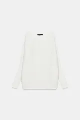 Sweater de punto blanco con textura acanalada horizontal, cuello barco, mangas largas amplias y corte holgado.