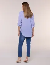 Camisa de corte clásico y silueta relajada con diseño de rayas verticales en blanco y negro. Presenta cuello camisero tradicional, cartera frontal con botones, un bolsillo aplicado en el pecho con rayas horizontales y mangas largas con sistema para arremangar.