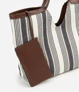 Cartera shopper de algodón con diseño a rayas en tonos neutros y detalles de ribetes y asas de hombro en PU marrón. Cuenta con una abertura central pronunciada y gran capacidad de almacenamiento.