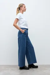 Pantalón de jean de corte recto y tiro alto, confeccionado en denim azul con una textura sutil de pequeños puntos en relieve.