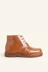 Bota acordonada de cuero vacuno con acabado charol color suela, con suela de goma tipo crepe y costuras reforzadas.