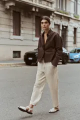 Sandalia plana tipo cangrejera color hueso, con tiras cruzadas y cierre mediante hebilla dorada.