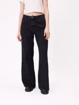 Jean de corte wide leg con tiro medio, confeccionado en denim de algodón color negro lavado. Presenta diseño de cinco bolsillos, cierre frontal con botón y cremallera, y botamanga recta.