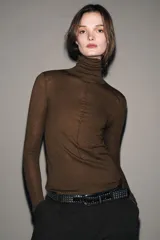 Jersey de punto con lana, de cuello subido y manga larga. Presenta un diseño ajustado con detalle de costuras verticales marcadas en el frente.