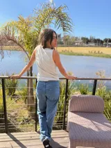 Musculosa gris oscuro de corte recto, con cuello redondo y diseño sin mangas. Presenta un pequeño bordado frontal de sol en tono amarillo y detalle de ribetes.