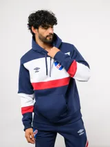 Canguro con capucha de Umbro del Club Nacional de Football, con diseño de bloques de color en azul, blanco y rojo. Presenta bolsillo frontal tipo canguro, cordones ajustables en la capucha y logos bordados del club y la marca.