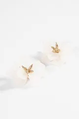 Caravanas tipo clip con diseño de flor de pétalos blancos de resina y centro metálico dorado.