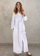 Vestido camisero largo blanco de lino, con cuello camisero, mangas largas, cierre frontal con botones y lazo para atar en la cintura.