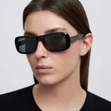 Lentes de sol con montura rectangular de perfil ancho y diseño minimalista. Cuentan con lentes polarizadas de color negro y montura de material bio-based.
