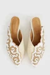 Zuecos color beige con bordado dorado de flores y pequeño tacón cuadrado.