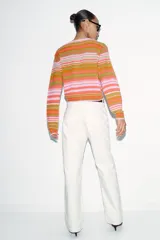 Chaqueta de punto con cuello en pico y cierre frontal de botones. Presenta un diseño de rayas horizontales en tonos naranja, verde y rosado, con mangas largas y puños ajustados.