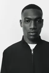 Campera bomber negra, de corte estándar, con cuello elevado acanalado, cierre frontal y bolsillos laterales con cierre. Presenta puños y bajo con ribete acanalado ancho.