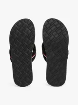 Ojotas negras con suela negra y blanca, y tiras de tejido trenzado con diseño chevron y detalle de cinta distintiva con los colores de la marca.