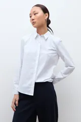 Camisa blanca de manga larga con cuello clásico y botones frontales ocultos.