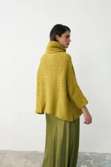 Sweater tipo poncho de tejido de punto grueso, color verde oliva, con cuello alto holgado y diseño de caída amplia.