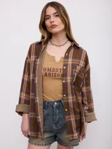 Camisa de flanela a cuadros en tonos marrones y azules, de corte oversize, con mangas largas y bolsillos frontales.