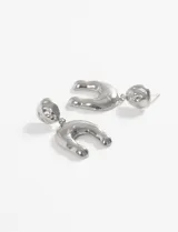 Par de caravanas plateadas de acero quirúrgico hipoalergénico con diseño curvo.