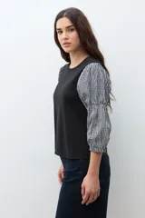 Remera de algodón negra con mangas abullonadas de tela con estampado vichy en blanco y negro, puños elásticos y cuello redondo.