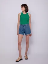 Short de jean azul de tiro alto con terminación desflecada en el ruedo. Presenta un lazo de tela para atar en la cintura y tiene un diseño de cinco bolsillos.