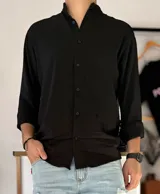 Camisa negra de manga larga con cuello mao y cierre frontal de botones negros.