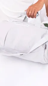 Bolso deportivo gris de nylon con doble asa y correa regulable. Cuenta con dos bolsillos exteriores con cierre, un bolsillo exterior de rejilla y un bolsillo interior con cierre.