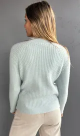 Sweater de punto con textura suave, color celeste, con diseño de ochos en el frente y tejido morley en mangas y espalda. Presenta cuello redondo a la base y mangas largas.