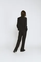 Blazer de cuello alto y manga larga con cierre frontal de botones metálicos en relieve. Presenta aberturas en los puños con botones y falsos bolsillos de vivo en el delantero.