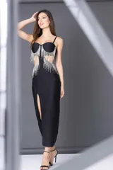 Vestido midi negro con escote corazón, breteles finos y falda ajustada con tajo lateral. Presenta apliques de flecos de strass en el busto y recortes laterales.