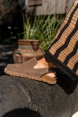 Zuecos de cuero marrón con talón descubierto y suela de goma.