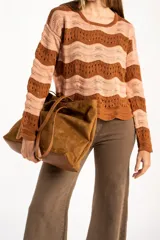 Sweater de tejido de punto con diseño de rayas horizontales onduladas en tonos marrón y beige. Presenta cuello redondo, mangas largas y corte oversize.