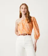 Blusa color durazno con estampado floral blanco, con un solo hombro y manga larga abullonada.