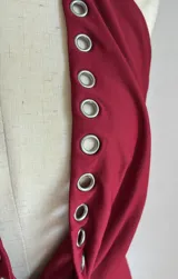 Minivestido rojo con escote halter pronunciado y detalle de ojalillos metálicos en el escote y el ruedo.