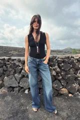 Body entallado color marrón oscuro con escote pronunciado en pico y manga sisa. Cierre en la parte inferior con botones a presión.