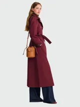 Bolso tipo crossbody de cuero, tamaño XS, con diseño de cubo y cierre de solapa con botón a presión. Incluye correa larga ajustable y cordones laterales decorativos.