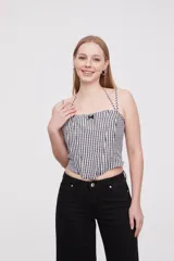 Top corto de escote cuadrado con breteles finos ajustables, confeccionado en tela con estampado de cuadros vichy en blanco y negro. Presenta un pequeño lazo decorativo en el centro del escote y un corte estilo corset con ruedo en punta.