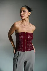 Corset rojo con cierre frontal con cremallera dorada y diseño geométrico en relieve.