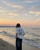 Remera blanca de manga corta con estampado gráfico en la espalda que incluye un personaje ilustrado, un gramófono y la inscripción "Kaboa Radio".