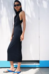 Vestido largo de corte fluido con cuello halter y espalda descubierta. Presenta un detalle de drapeado lateral y bajo recto.