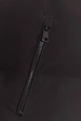 Chaleco acolchado de cuello subido con cierre frontal de cremallera. Presenta bolsillos laterales con cremallera y bajo ajustable con cordones elásticos.